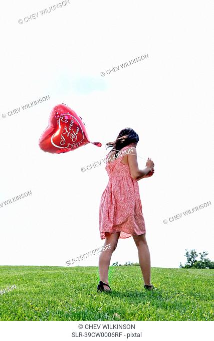 Teenager carrying heart-shaped balloon