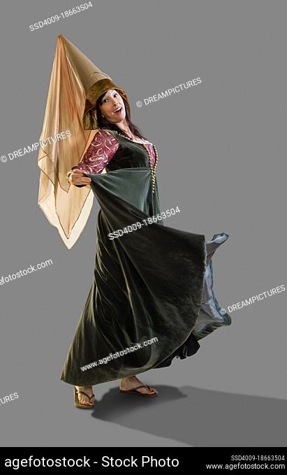 Full length portrait of a medieval Princess dancing and turning in circles, against gray background