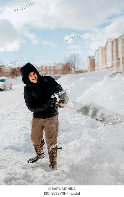 Man clearing snow-covered road with shovel, Toronto, Canada