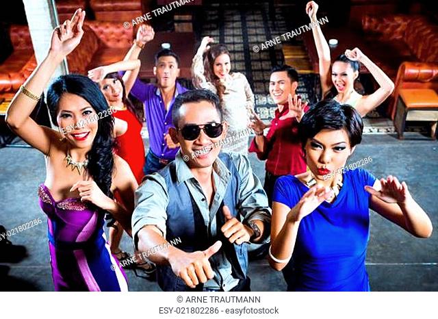 Asian people partying on dance floor in nightclub