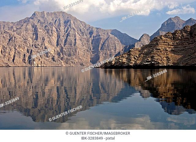 Reflection of a barren mountain range in the Khor Ash Sham Fjord, on Seebi Island, Musandam Governorate, Oman