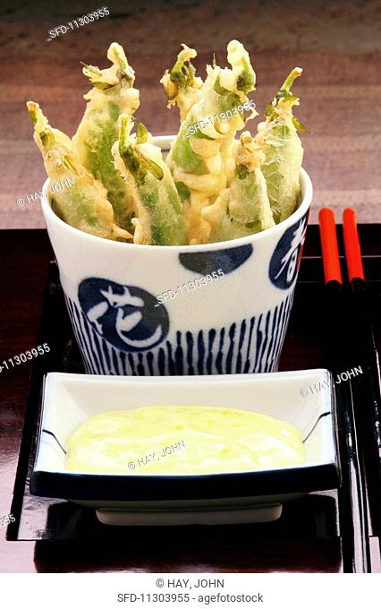 Pea pod tempura with a dipping sauce served in oriental crockery