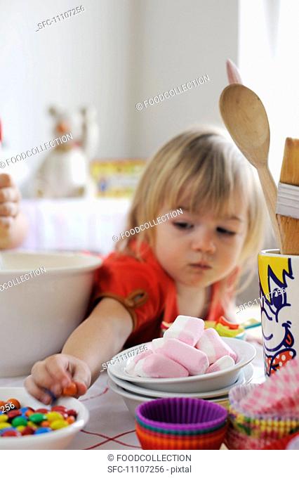 Young girl reaching for sweets from the bowl while baking