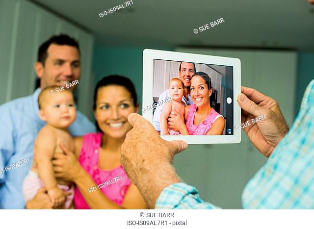 Over shoulder portrait of mid adult couple and baby daughter taken on digital tablet