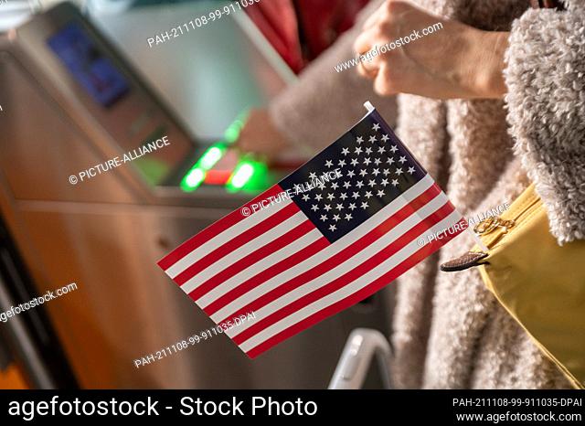 08 November 2021, Hessen, Frankfurt/Main: A woman walks through the boarding area at Frankfurt Airport with her boarding pass and a USA flag for a Lufthansa...