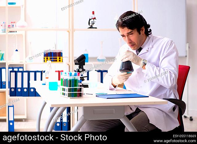 Young handsome chemist working in the lab