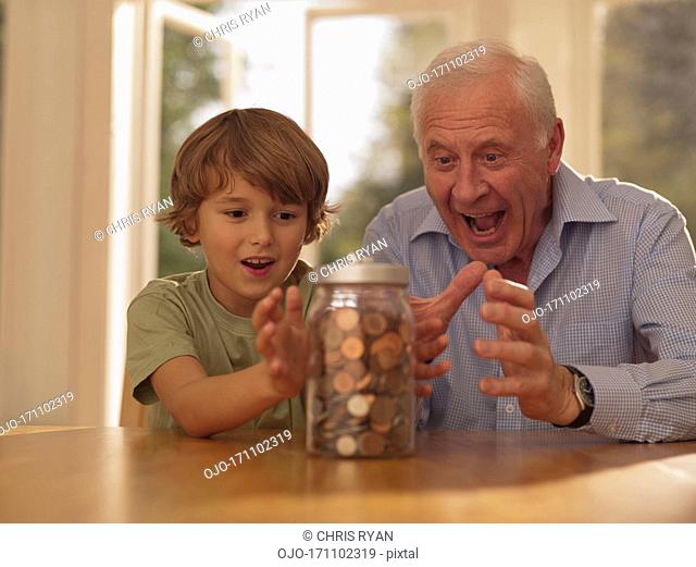 Grandfather and grandson hold at jar full of coins