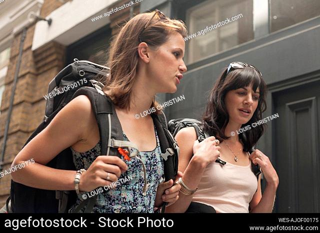 Beautiful female backpackers talking while walking in city