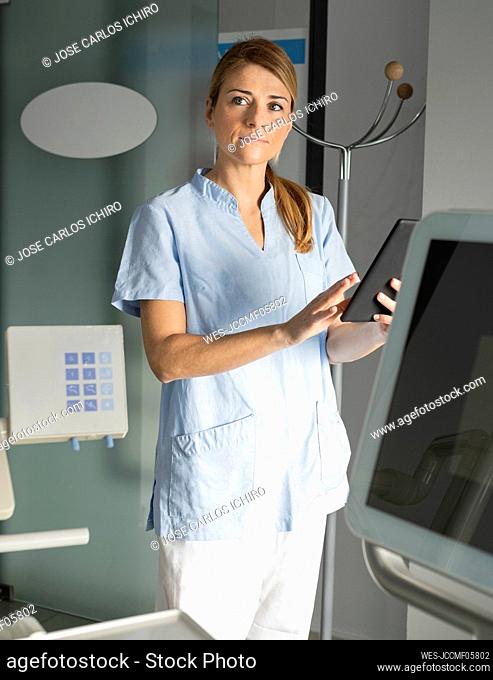 Dentist with tablet PC standing in dental clinic