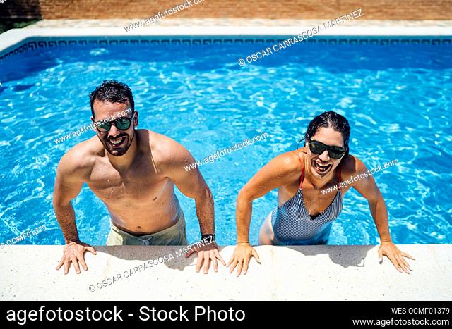 Couple with sunglasses at pool edge