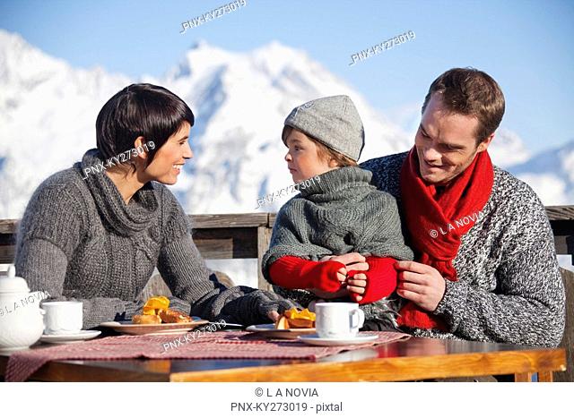 Couple and daughter eating on balcony at ski resort