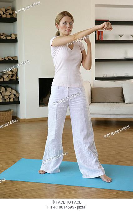 A blonde woman exercising in her hall, Tae Bo