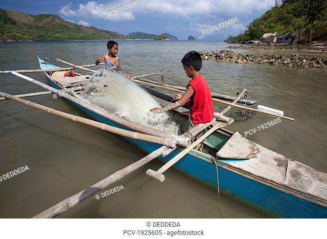 two young filipino boys work on their family's wooden bangka boat in the tiny fishing village of vigan near snake island and el nido, vigan, bacuit archipelago