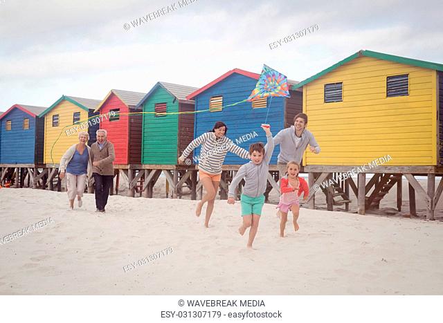 Happy multi-generation family running by beach huts at beach