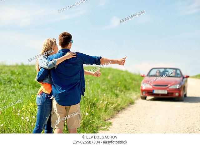 road trip, hitchhike, travel, gesture and people concept - happy couple hitchhiking and stopping car at countryside