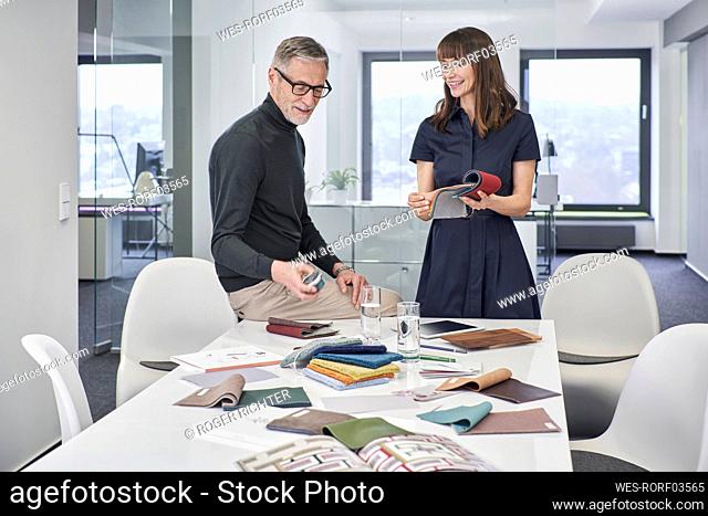 Creative businessman and businesswoman discussing swatches in office