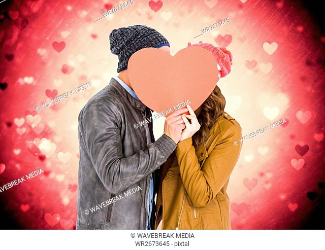 Romantic couple hiding their face behind heart