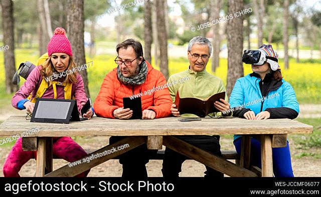 Mature men and women sitting at picnic table in forest