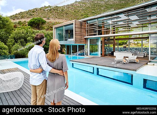 Heterosexual couple looking at modern house while standing outdoors