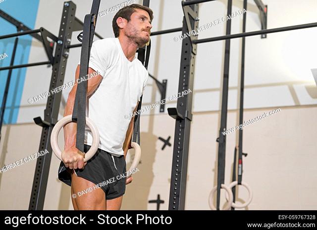 Young Male Athlete exercising With Gymnastic Rings In The Gym. High quality photo