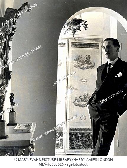 Hardy Amies, fashion designer, standing inside an archway in his first London flat