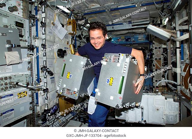 Astronaut Daniel W. Bursch, Expedition Four flight engineer, moves equipment in the Destiny laboratory on the International Space Station (ISS)