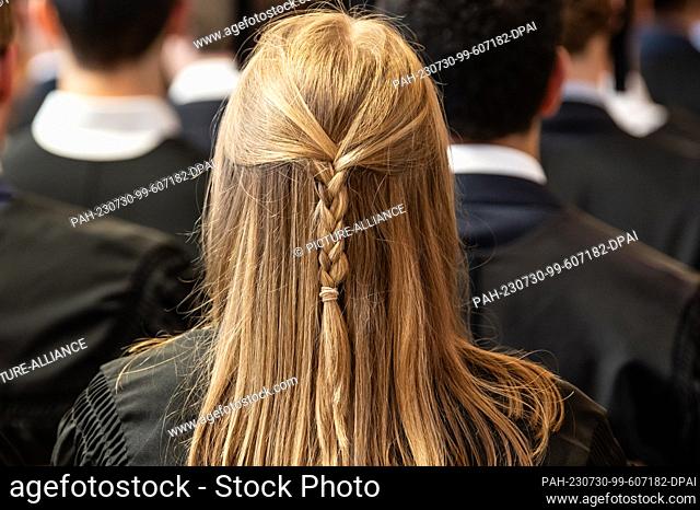 SYMBOL - 28 July 2023, Baden-Württemberg, Mannheim: A young woman wears braided hair at her graduation ceremony in the university