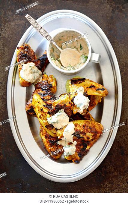 Grilled chicken wings marinated in yoghurt and curry with a yoghurt and coriander dip