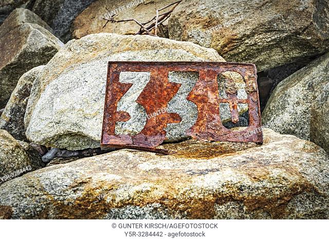 A rusted signpost with the number 330 stands on stones. The Sign is located on the Beach of the Baltic Sea in Kolobrzeg, West Pomeranian, Poland, Europe