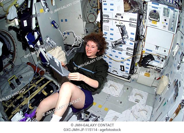 Now a member of the STS-105 crew, departing Expedition Two flight engineer Susan J. Helms works out on the ergometer device on the mid deck of the Space Shuttle...