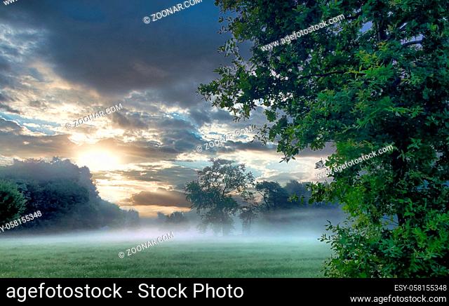 A dramatic colorful sky over a misty rural nature landscape. High quality photo