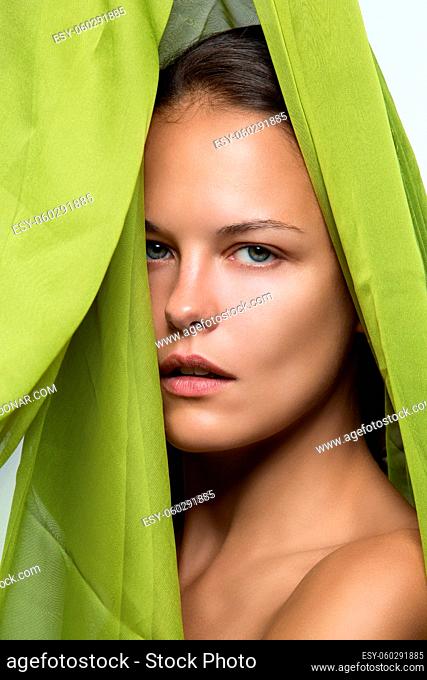 Closeup portrait of beautiful young woman covered with green textile. No makeup