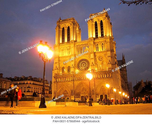 The famous cathedral of Notre-Dame shines illuminated at dusk on the Ile de la Cite, the island in the middle of the River Seine, in central Paris, France