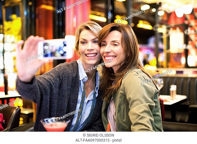 Women in bar taking self-portrait with photophone