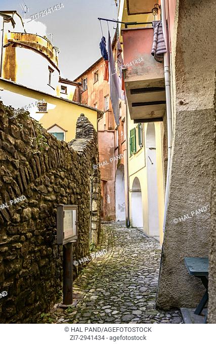 foreshortening of lane near arches under old picturesque bending covered walkway, shot in bright late summer light at Varese Ligure, Genova, Liguria, Italy