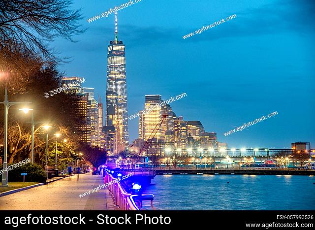 Downtown Manhattan night skyline from Hudson River Park. Skyscrapers lights and city pier