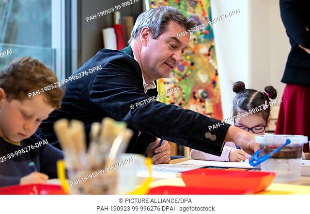 23 September 2019, Bavaria, MŸnchen: Markus Söder (CSU), Prime Minister of Bavaria, paints with the children during a tour of the Municipal House for Children