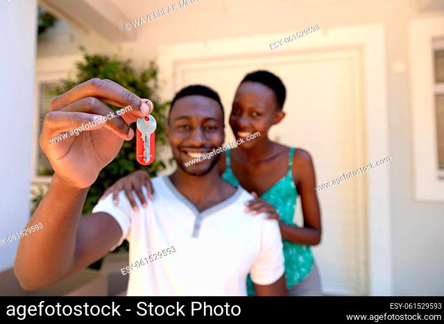 Portrait of african american couple moving house holding keys and smiling