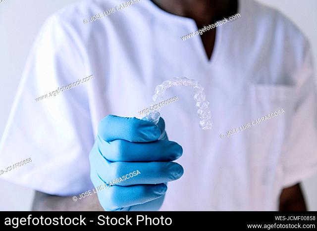 Close-up of afro doctor holding dental aligner