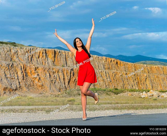 Young woman joyful hands-up standing on one leg