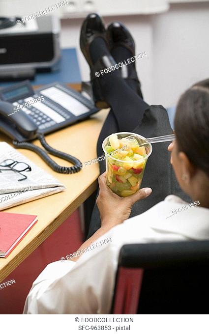 Woman eating fruit salad in the office