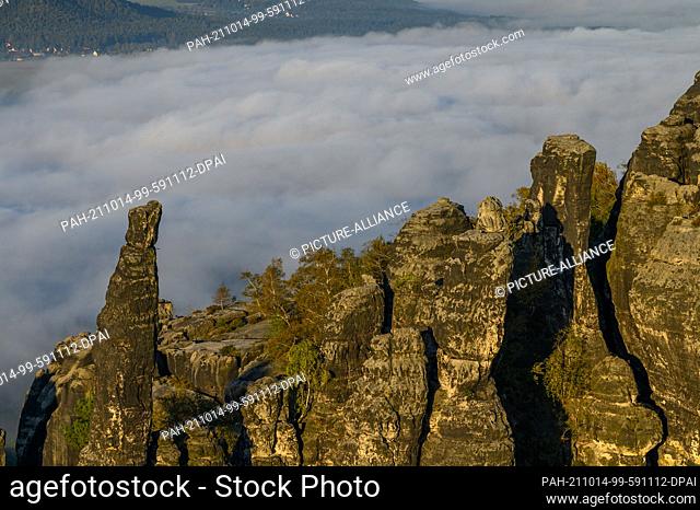 10 October 2021, Saxony, Bad Schandau: View from the Schrammstein lookout in Saxon Switzerland of the rocks of the Schrammsteine and the fog passing by in the...
