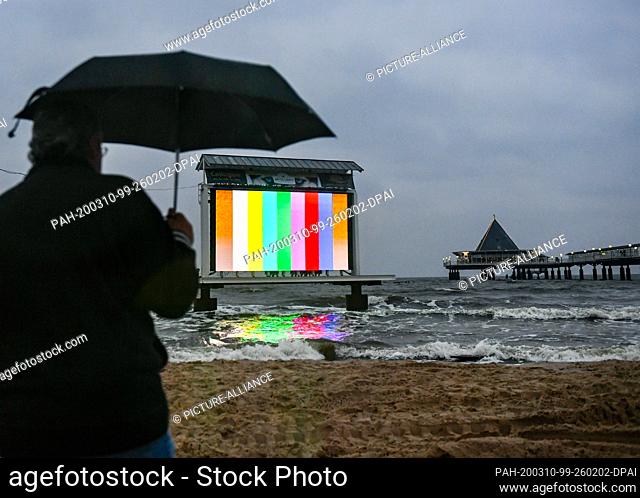 06 March 2020, Mecklenburg-Western Pomerania, Heringsdorf: A large LED video wall in the water of the Baltic Sea can be seen at the pier in the evening at dusk
