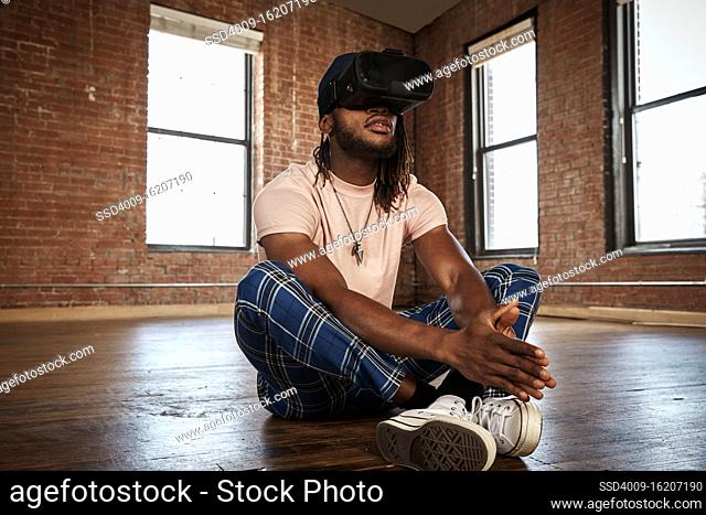 portrait of stylish young ethnic man wearing VR headset in empty loft space