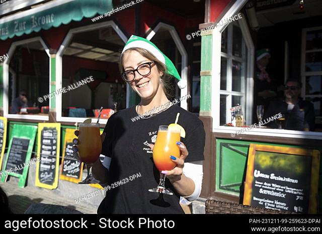 11 December 2023, Spain, Palma: Noemi, an employee of the restaurant ""Zur Krone"" on Arenal beach, wears a Santa hat during a sunny day with a record...