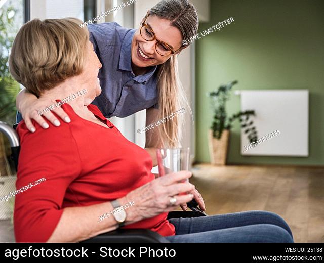 Smiling caregiver looking at disabled woman in wheelchair