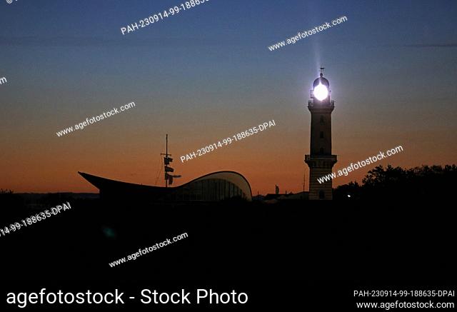 14 September 2023, Mecklenburg-Western Pomerania, Warnemünde: In the early morning before sunrise, the lighthouse in the Baltic Sea resort of Rostock-Warnemünde...