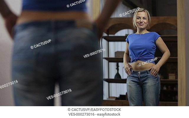 Excited woman in old jeans after losing weight