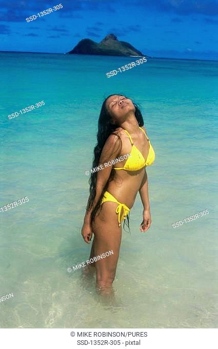 Young woman standing in water on the beach, Lanikai Beach, Oahu, Hawaii, USA