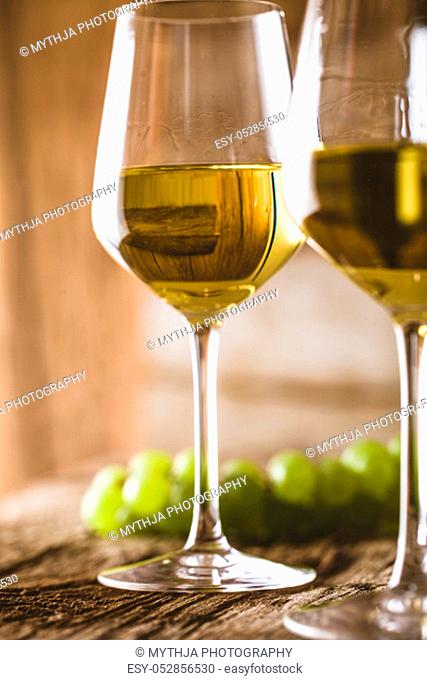 Wine. Glass of white wine in wine cellar. Old white wine on wood